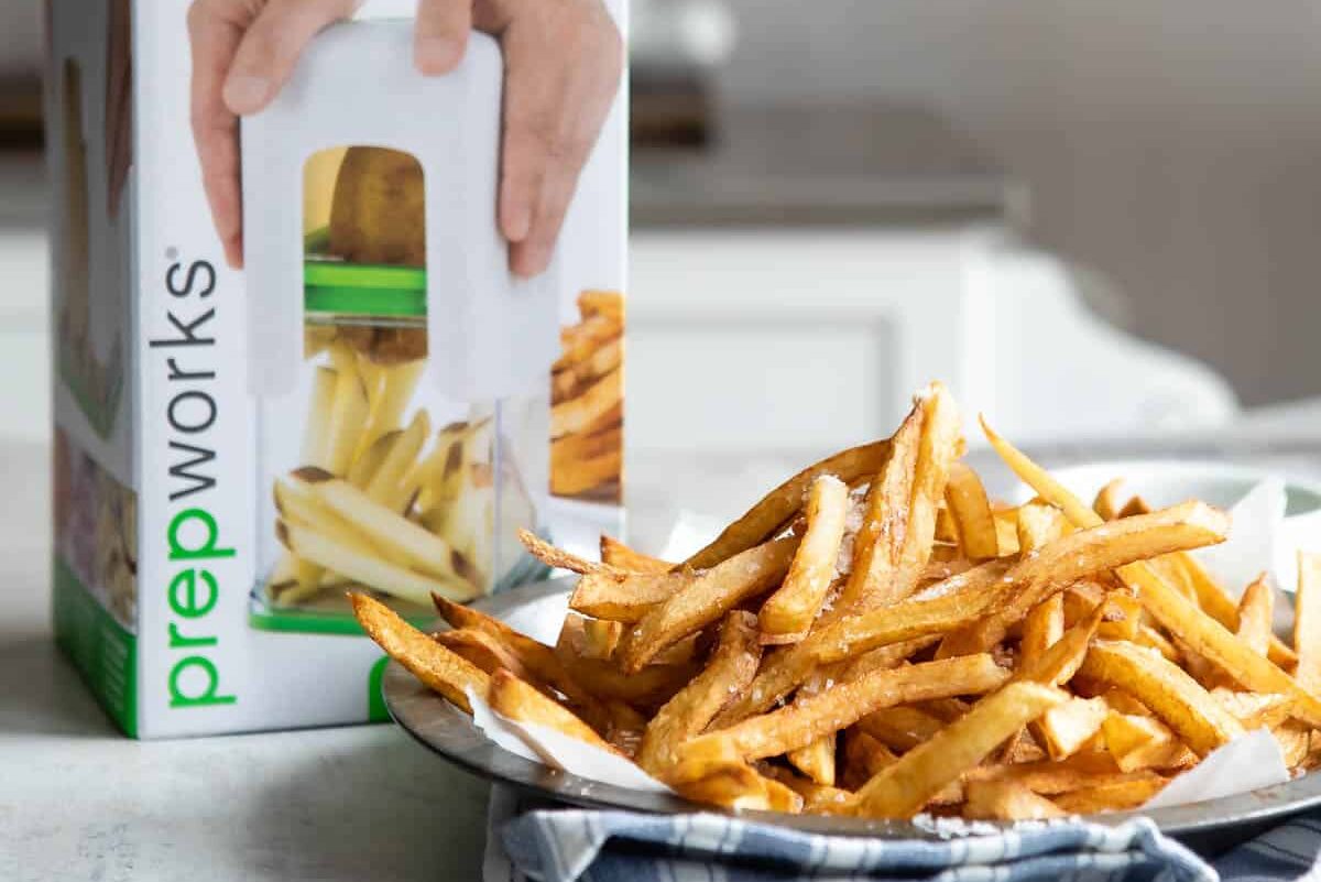 A progressive French Fry cutter next to a pile of French fries.