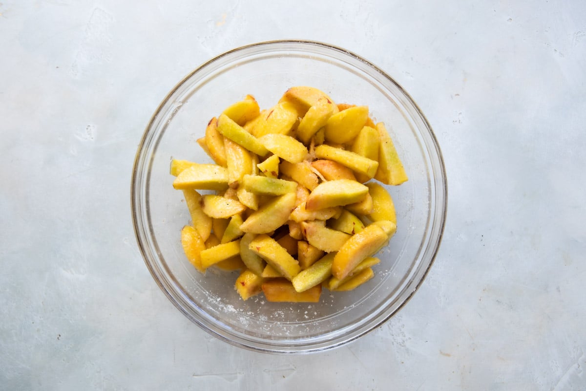 A bowl of peaches tossed in sugar and spices.