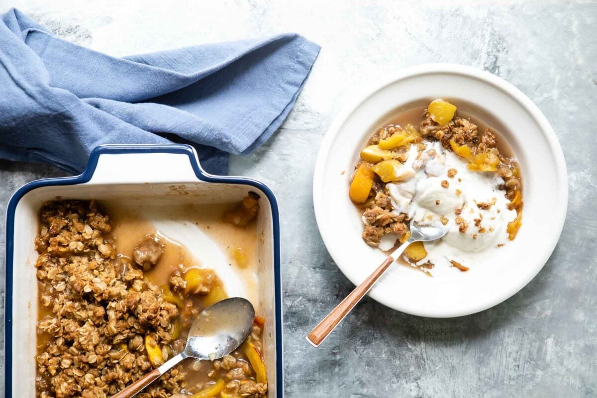 A bowl of Peach Crisp with a scoop of vanilla ice cream on top.