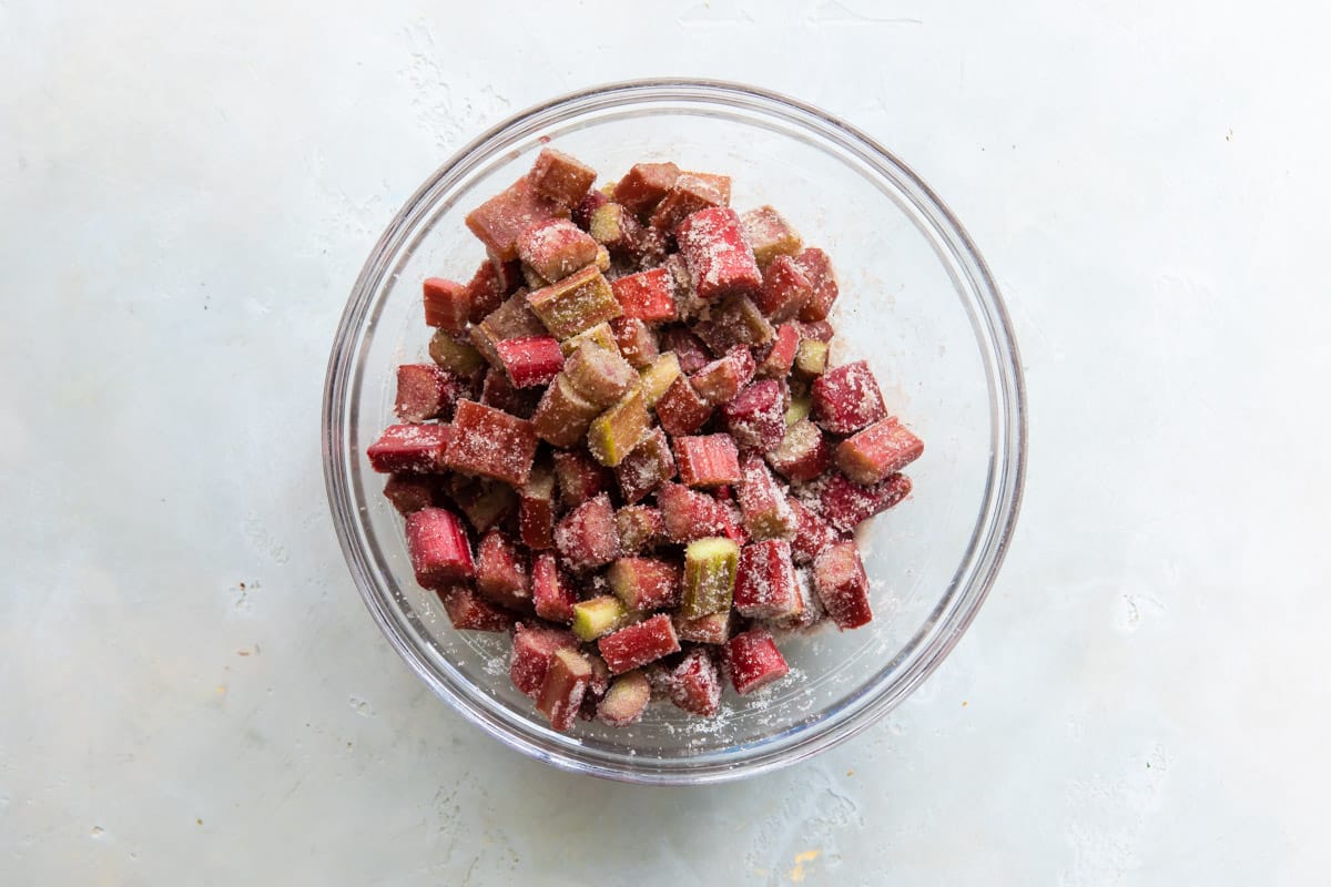 A bowl of chopped rhubarb tossed with sugar and spices.