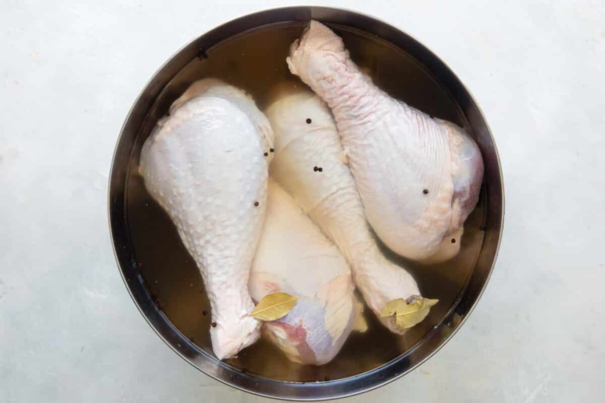 Raw turkey legs in a brining solution.
