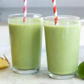 2 glasses of Spinach Smoothie with ingredients nearby.