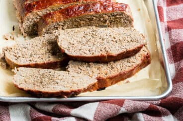 A turkey meatloaf with slices cut off on a baking sheet.