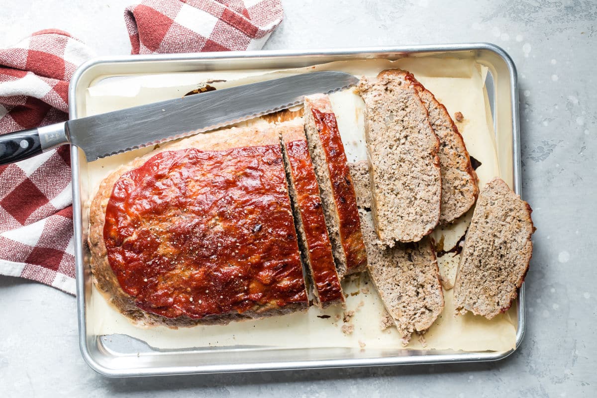 A turkey meatloaf with slices cut off on a baking sheet.