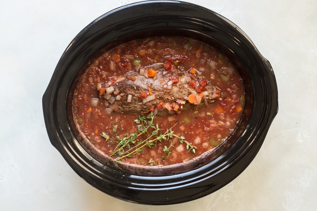 A slow cooker filled with beef ragu.