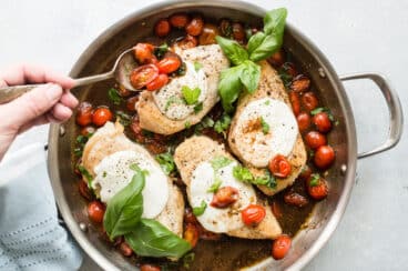 Caprese chicken in a stainless steel skillet.