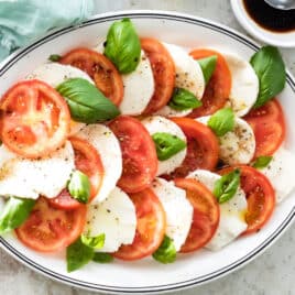 Caprese salad on a white serving dish with a blue rim.