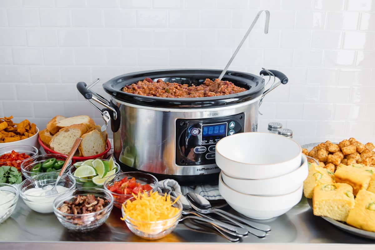 A crockpot full of chili with toppings on a Chili Bar.