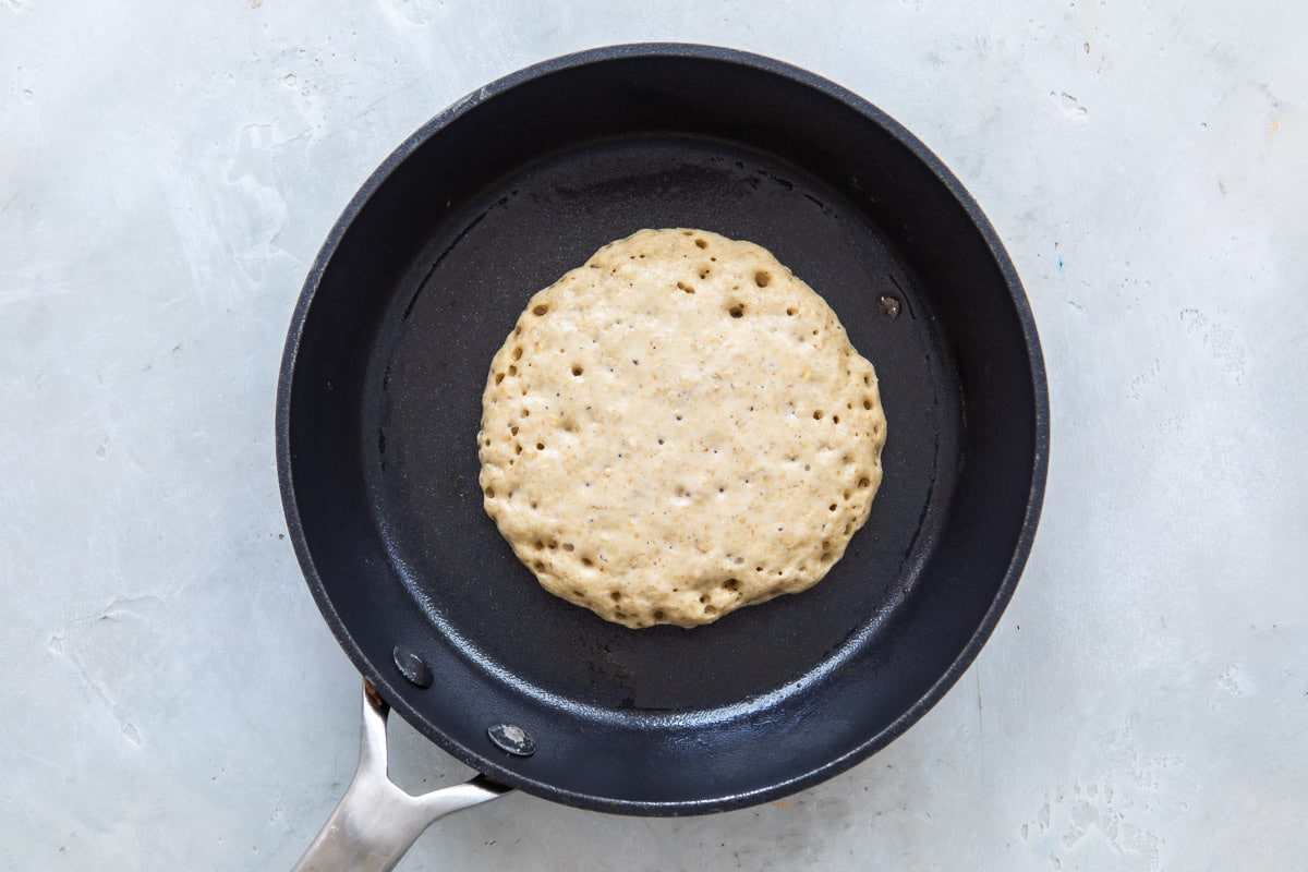 Pancake batter in a skillet before flipping.