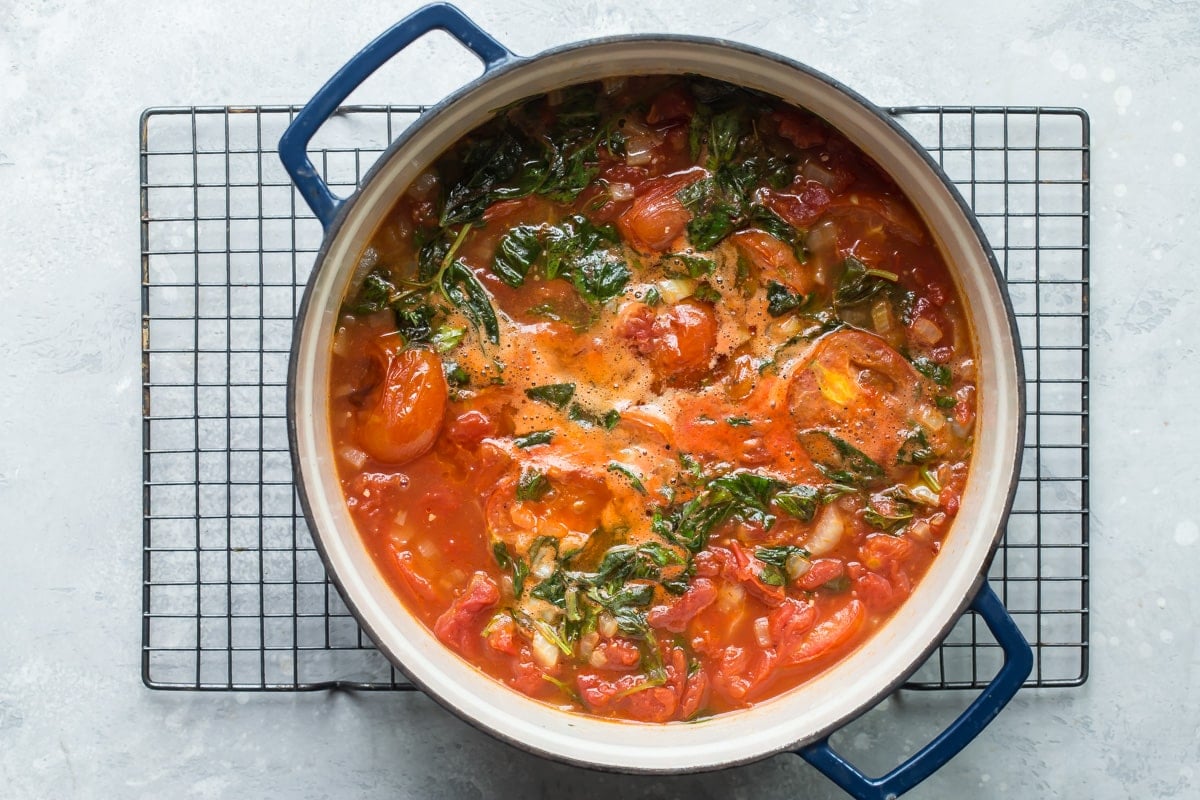 A Dutch oven with tomato soup ingredients in it.