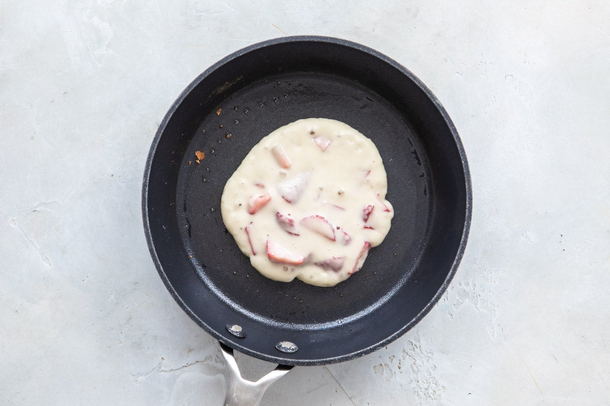 Pancake batter in a skillet before flipping.