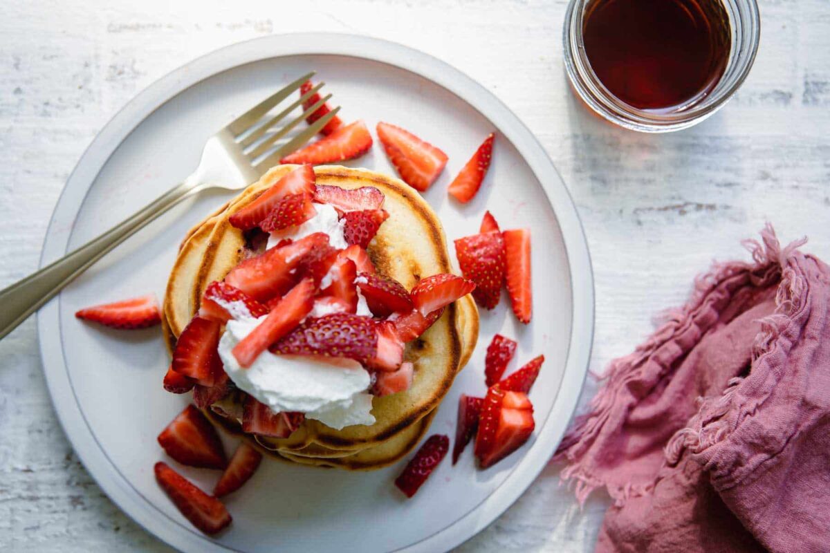 A stack of strawberry pancakes on a plate.