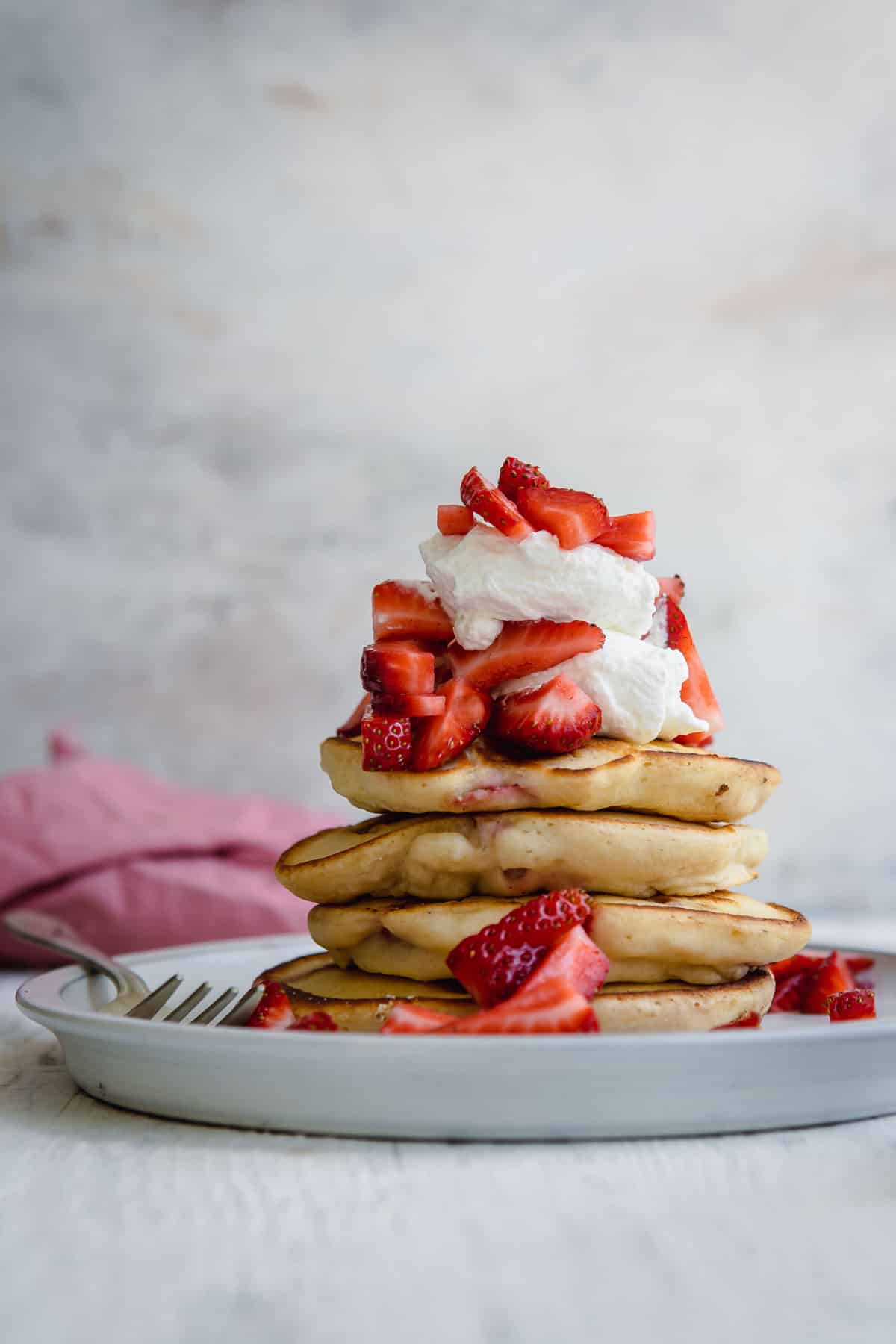 A stack of strawberry pancakes on a plate.