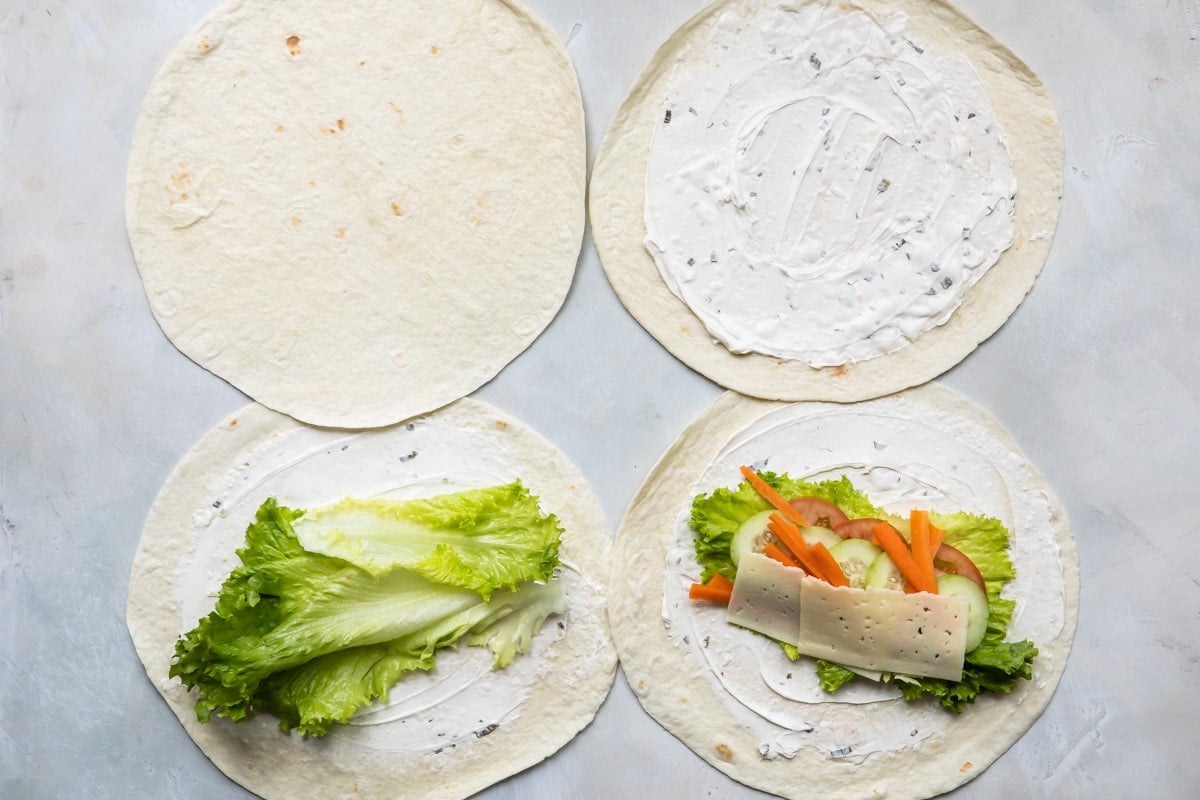 Building a veggie wrap on a marble surface.