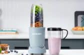 A portable blender on a countertop with a smoothie cup next to it.
