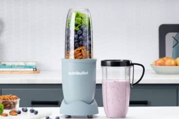 A portable blender on a countertop with a smoothie cup next to it.