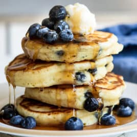 A stack of four blueberry pancakes on a plate.