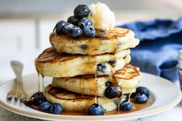 A stack of four blueberry pancakes on a plate.