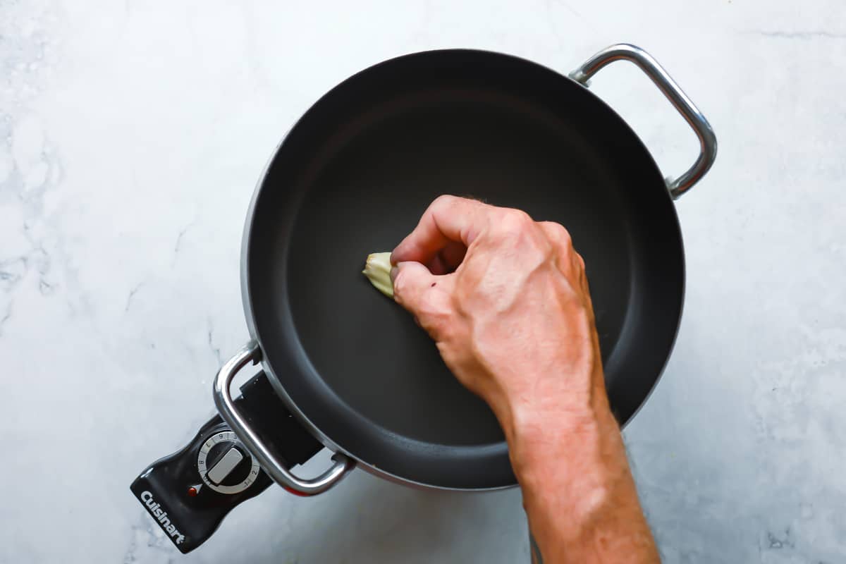 Rubbing a fondue pot with garlic.