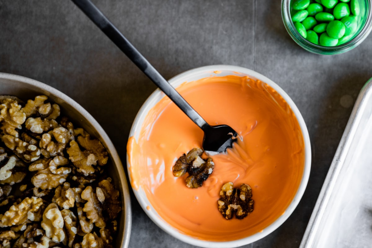 A bowl of melted candy coating for making Halloween walnuts.