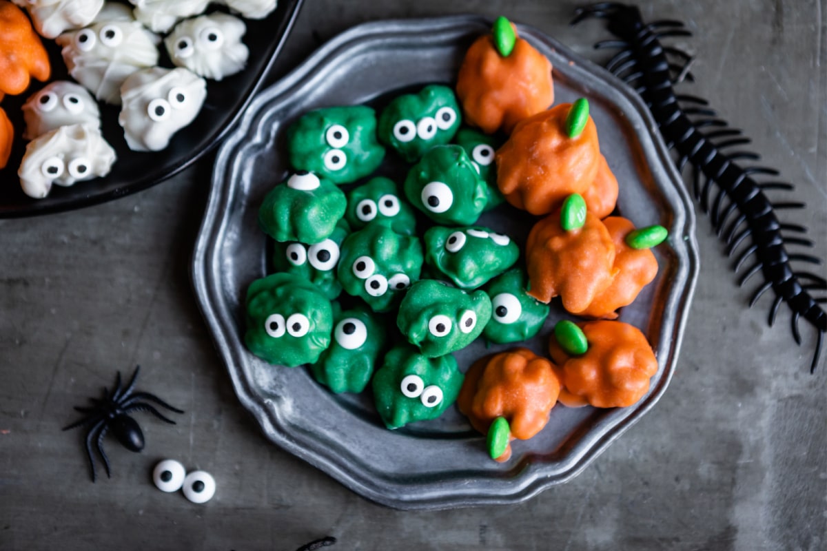 A plate of Halloween walnuts decorated to look like pumpkins and zombies.