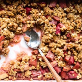 A pan of rhubarb crisp with a spoon resting in it.
