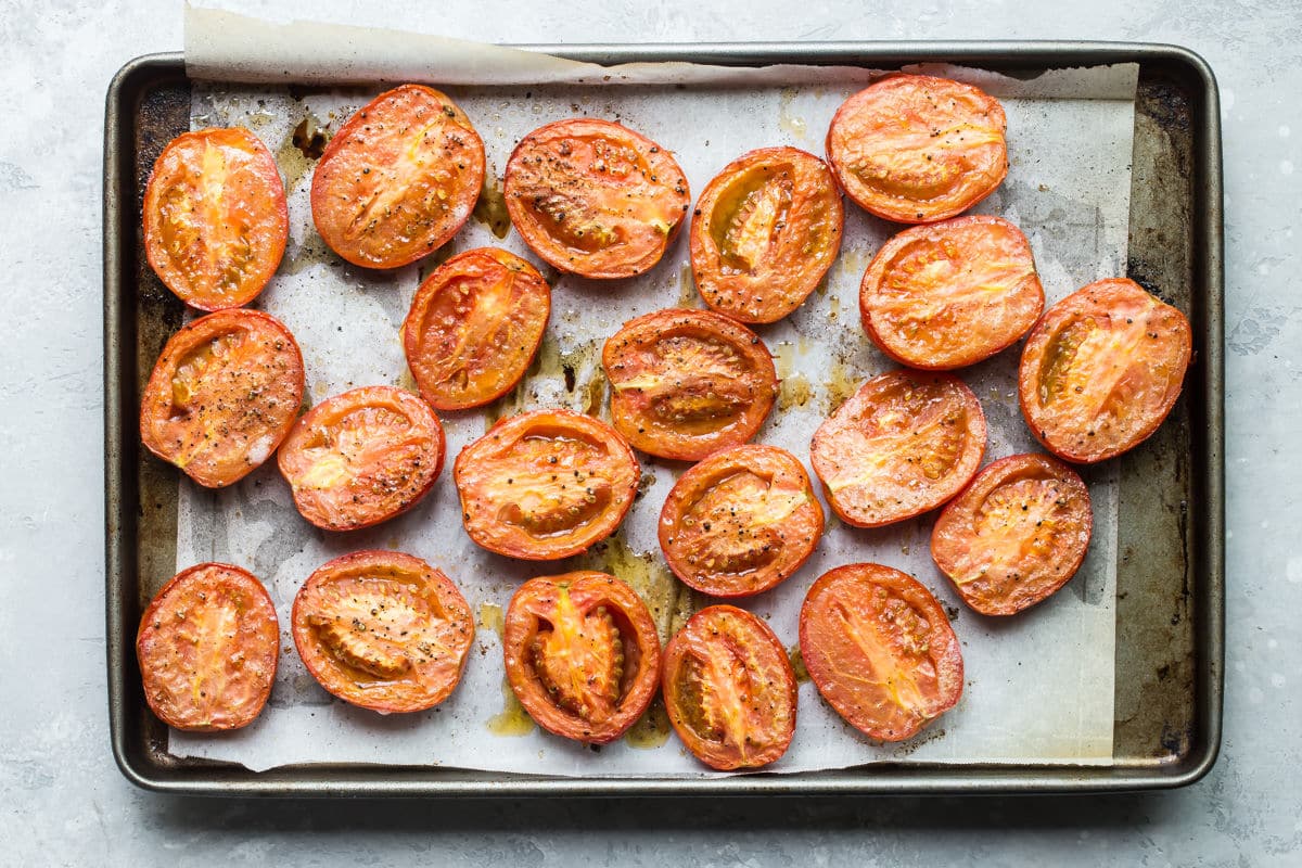 Roasted tomatoes on a rimmed baking sheet.