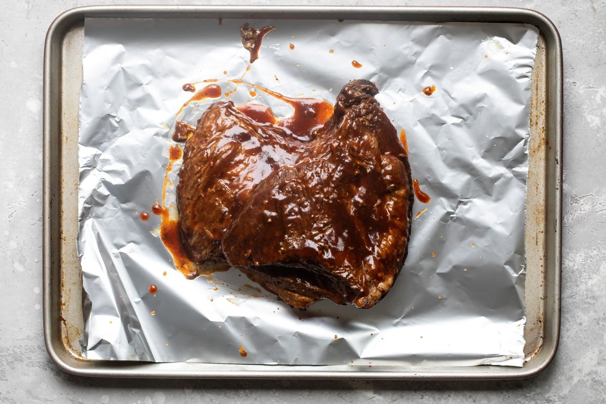 A slow cooker beef brisket on a metal foil lined pan.