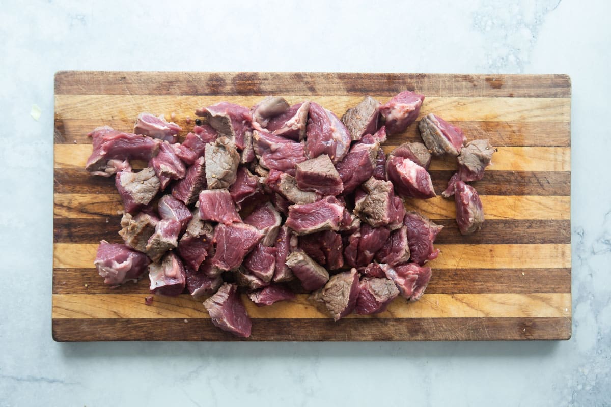 Chunks of boneless beef roast cut up on a cutting board.