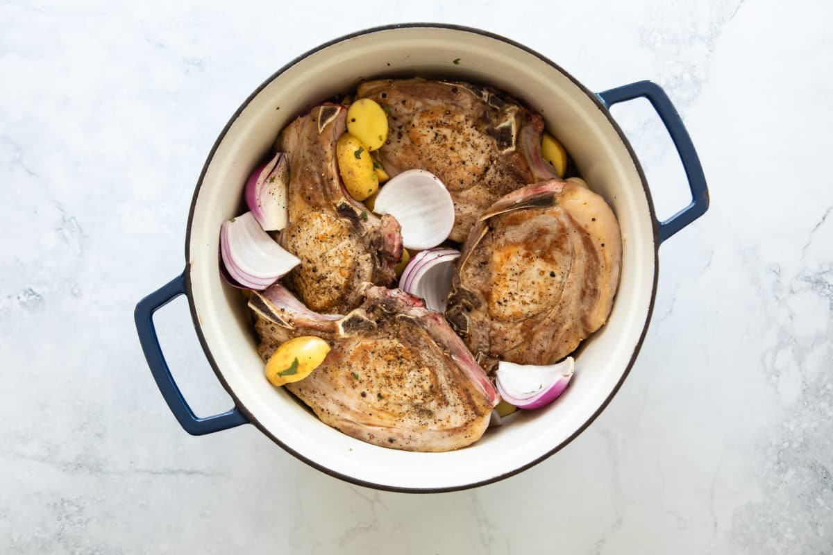 Vegetables and pork chops in a Dutch oven.