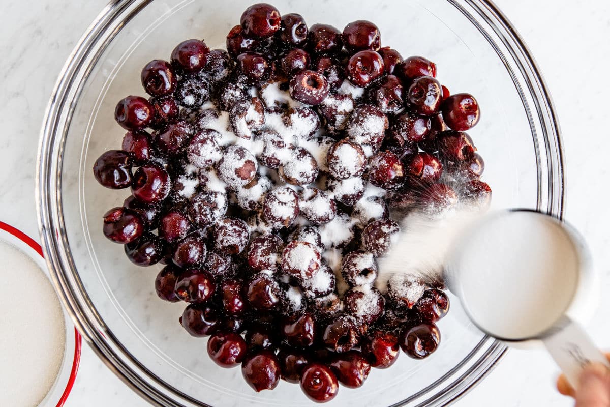 Cherries mixed with sugar in a bowl.