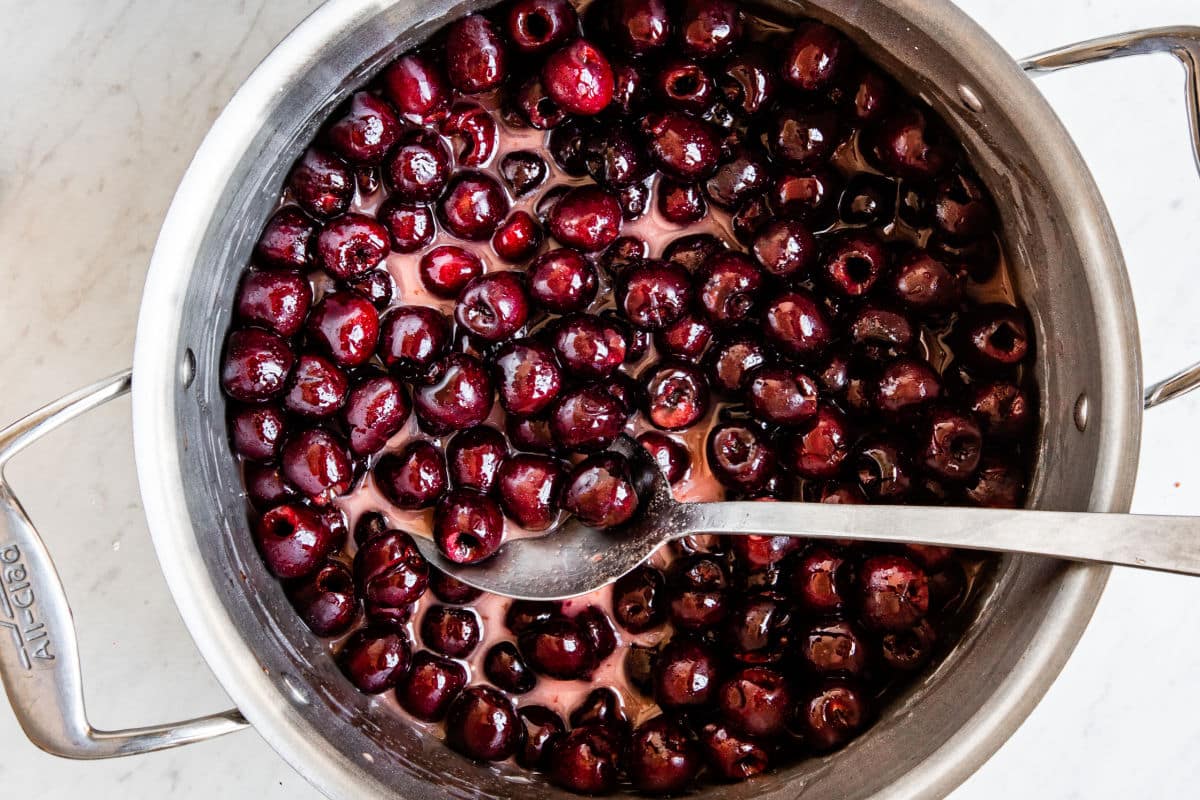 Cherries mixed with sugar in a pot.