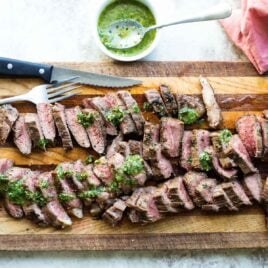 Chimichurri steak on a wooden cutting board.