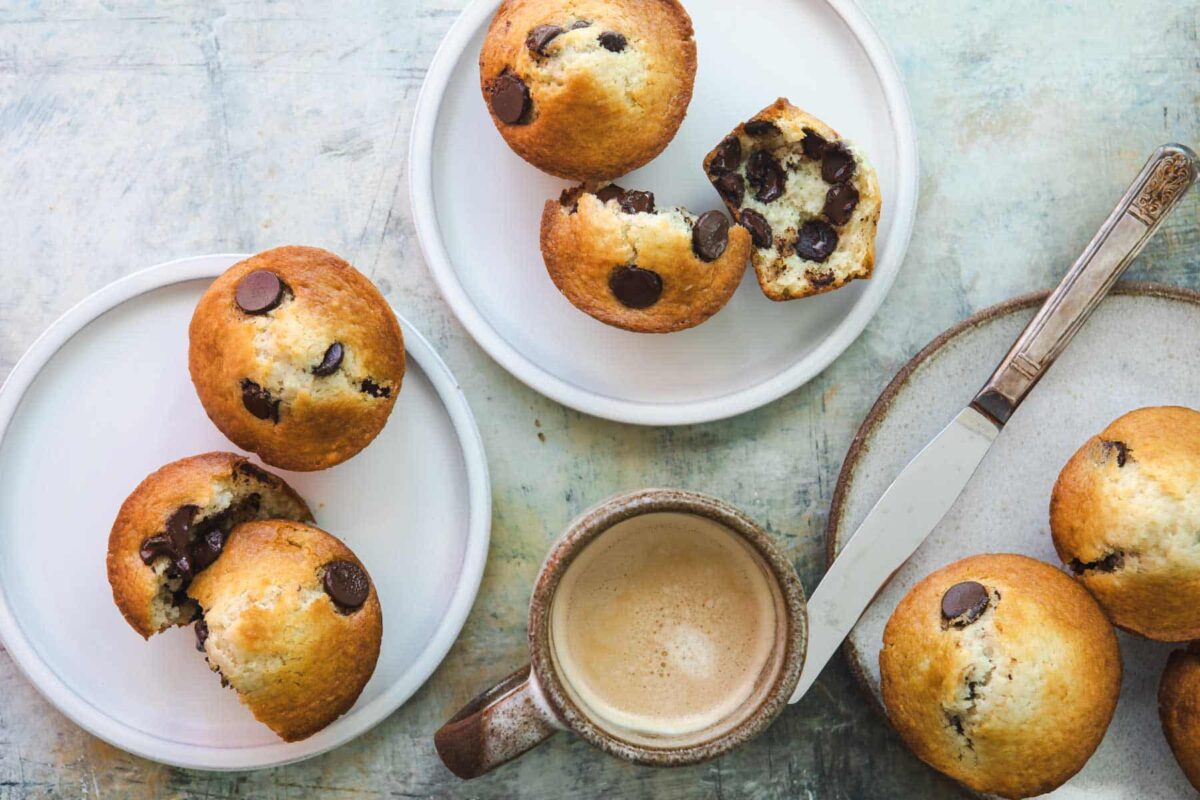 Chocolate chip muffins on a plate next to a cup of coffee.