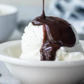 Chocolate sauce being drizzled on a scoop of vanilla ice cream.