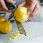 A lemon being zested with a zester.