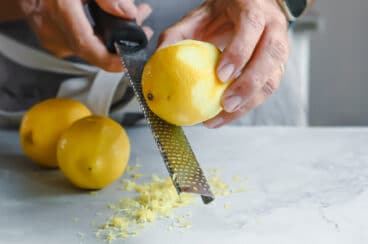 A lemon being zested with a zester.