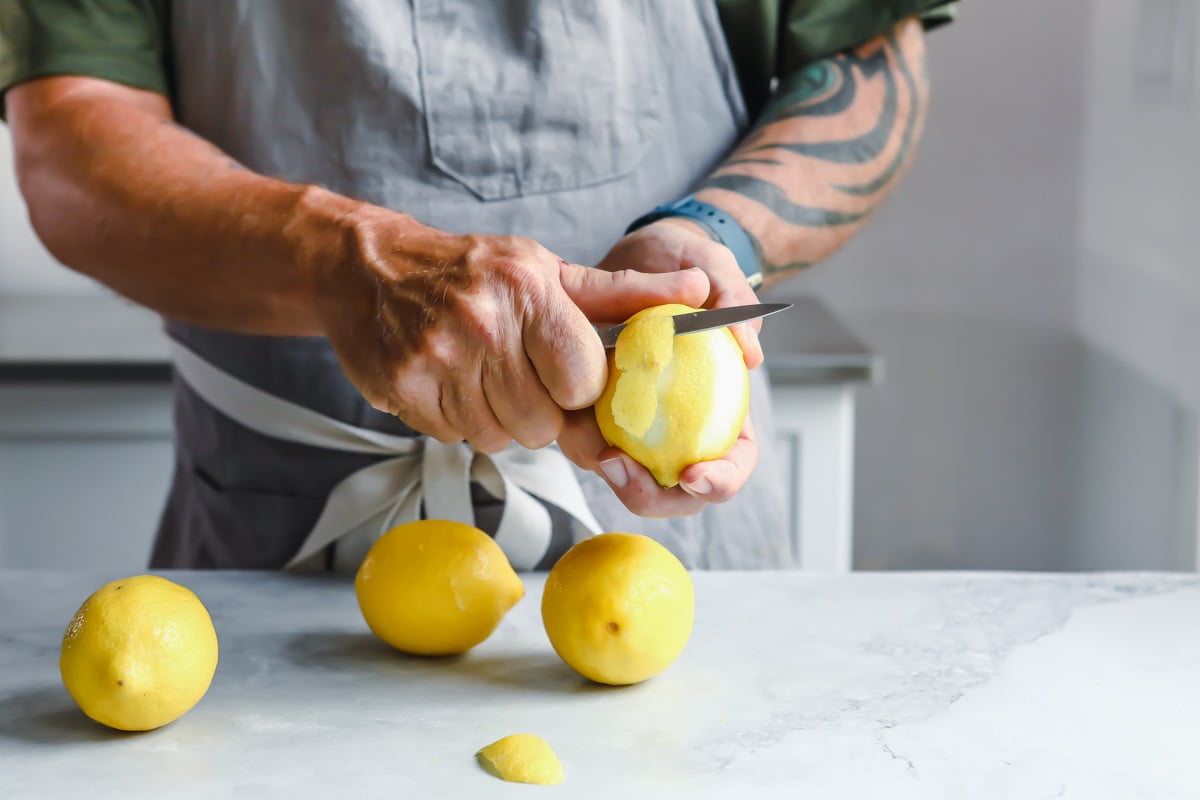 A lemon being peeled with a knife.
