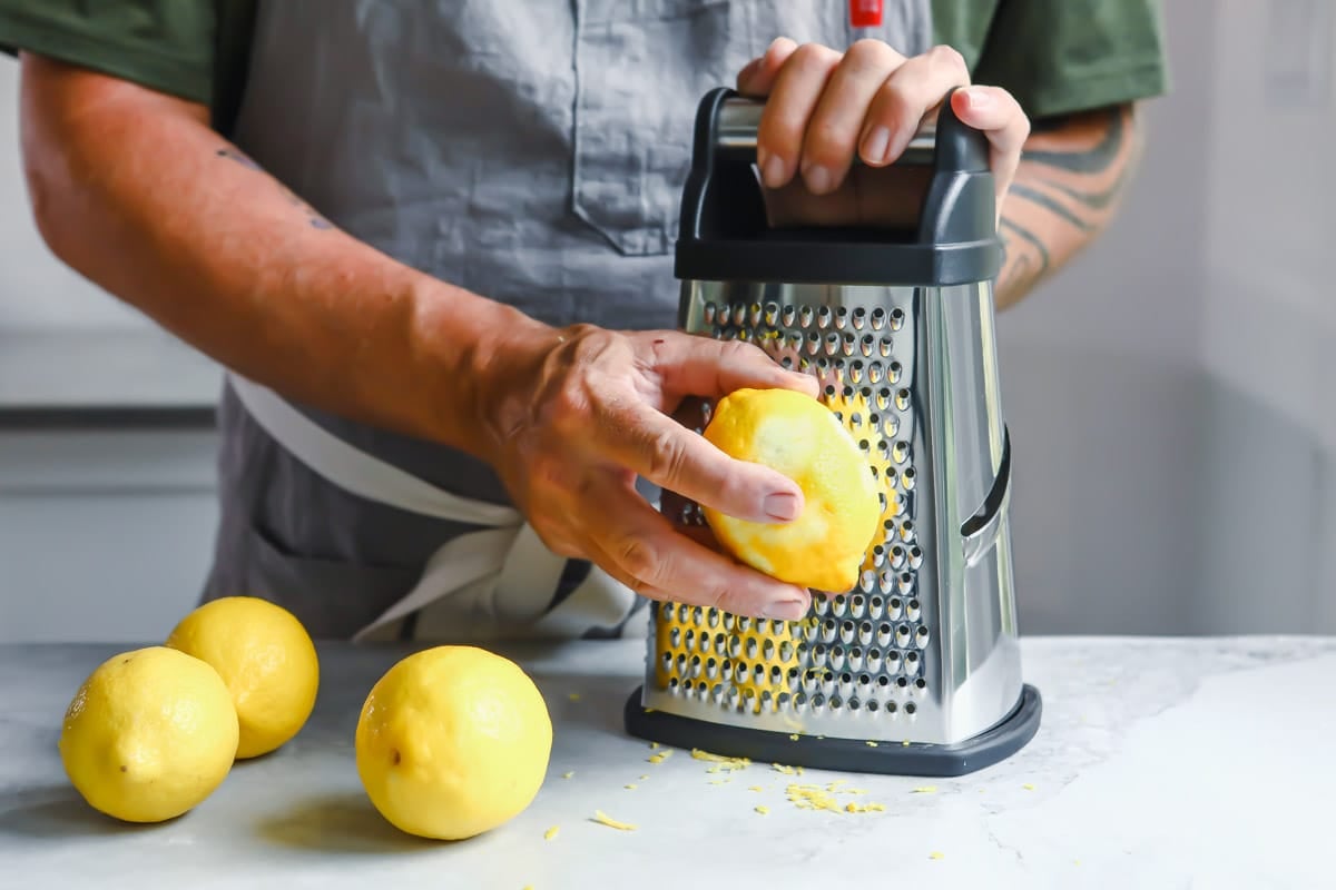 A lemon being zested on a grater box.