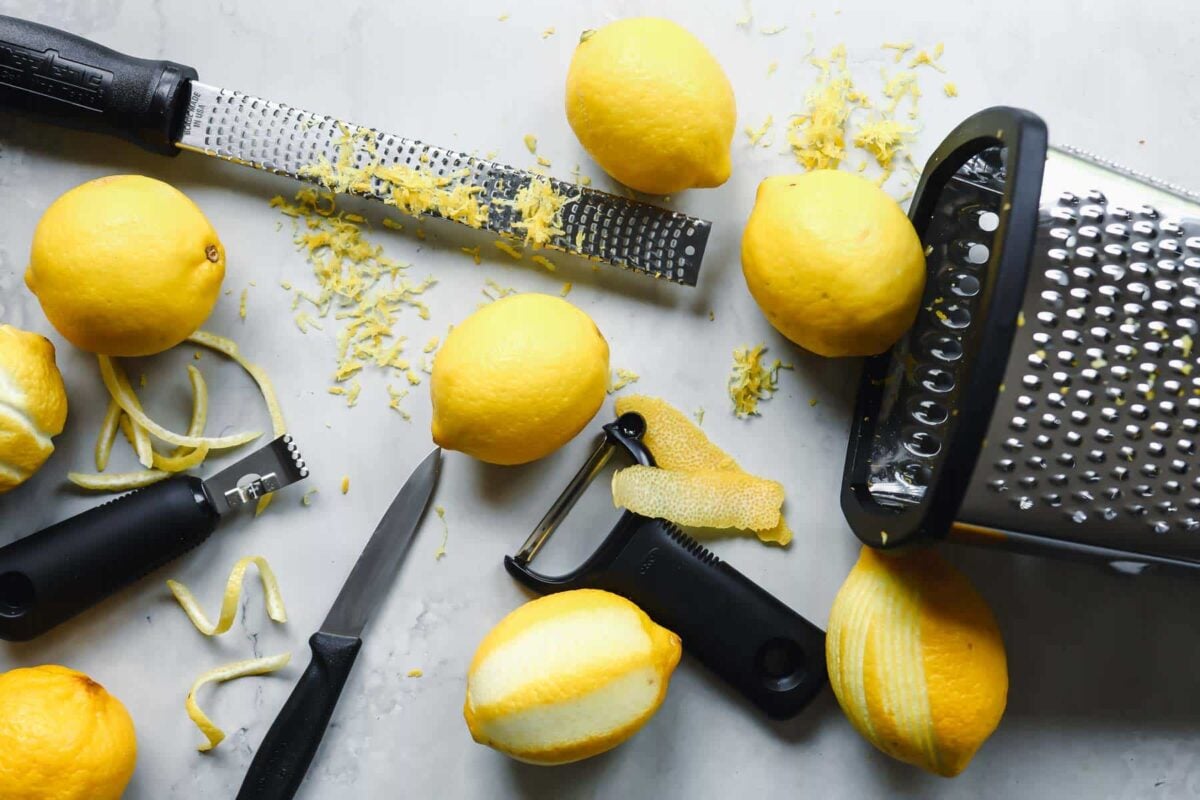 Zested lemons and tools to zest a lemon on a countertop.