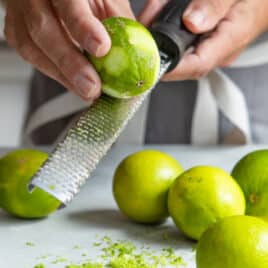 A lime being zested with a zester.