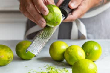 A lime being zested with a zester.