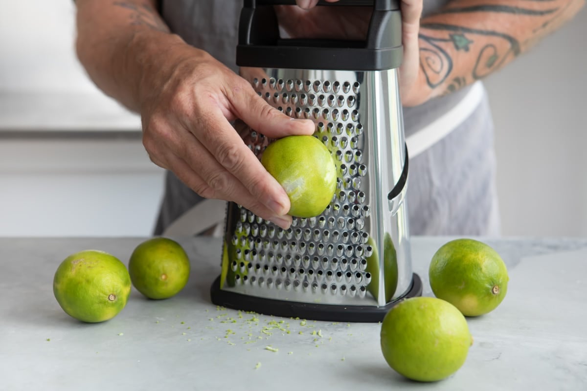 Someone zesting a lime on a box grater.