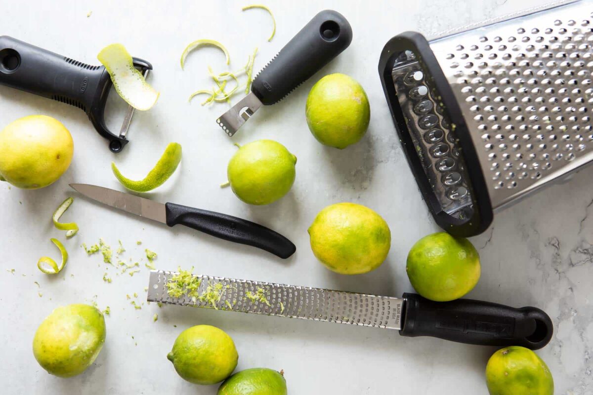 Zested limes and tools to zest a lime on a countertop.