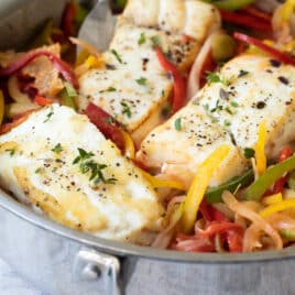 Pan-Seared Halibut with peppers and olives in a silver skillet.