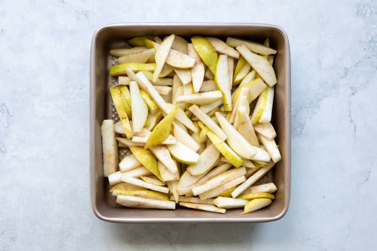 A baking dish of pears tossed with cinnamon and sugar.