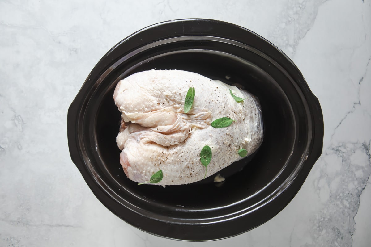 A raw turkey breast in a crockpot.