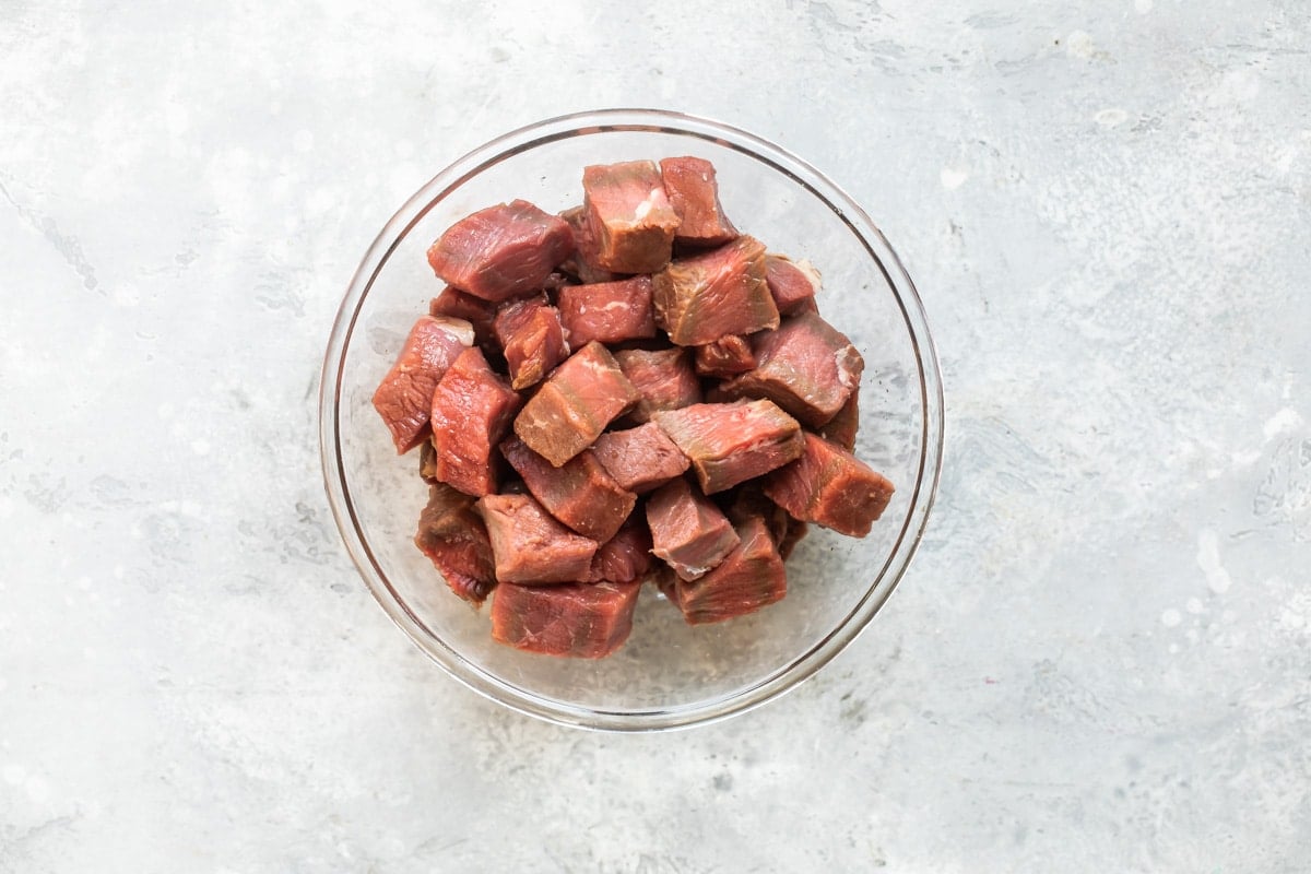 Uncooked steak tips in a clear bowl.
