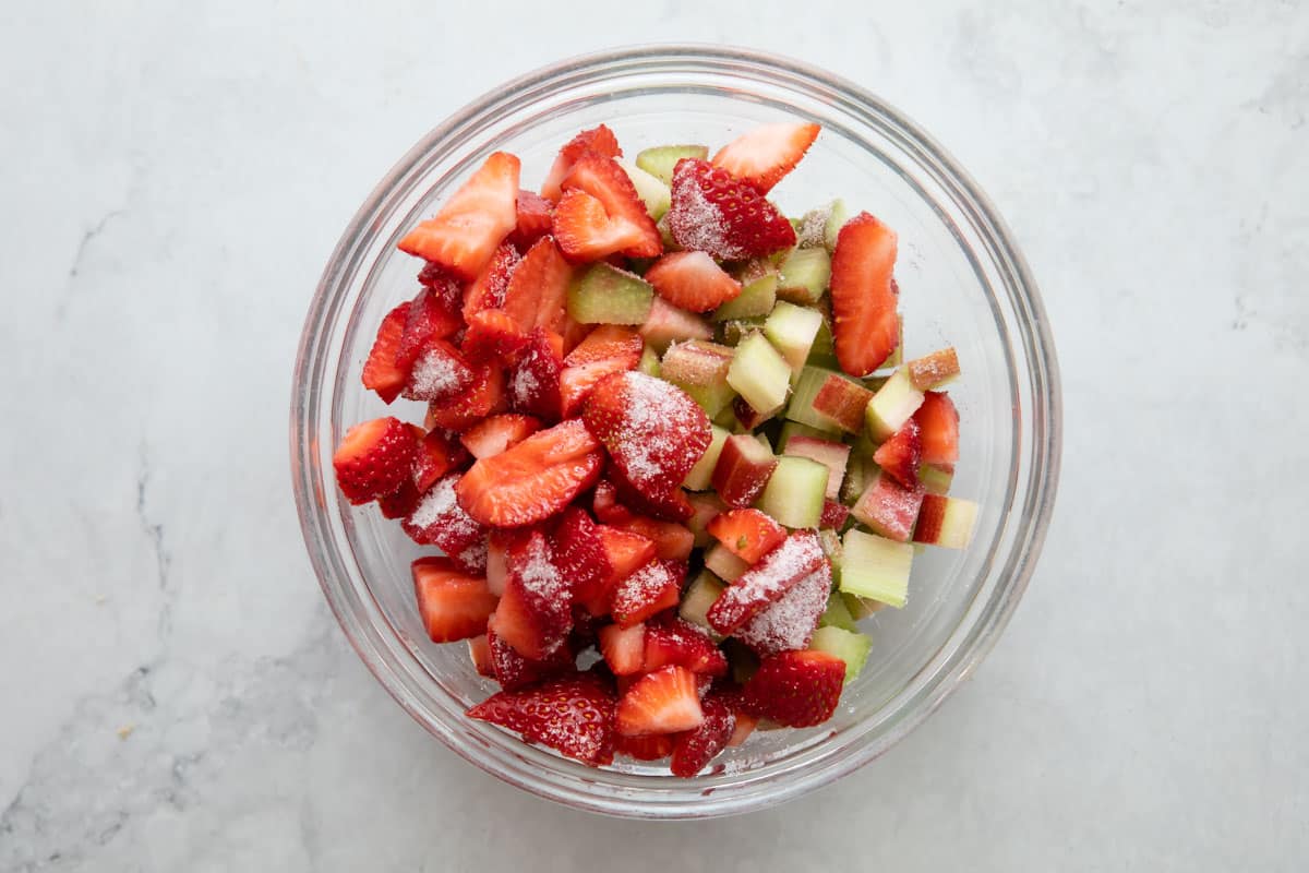 Strawberry, rhubarb and sugar in a glass bowl.