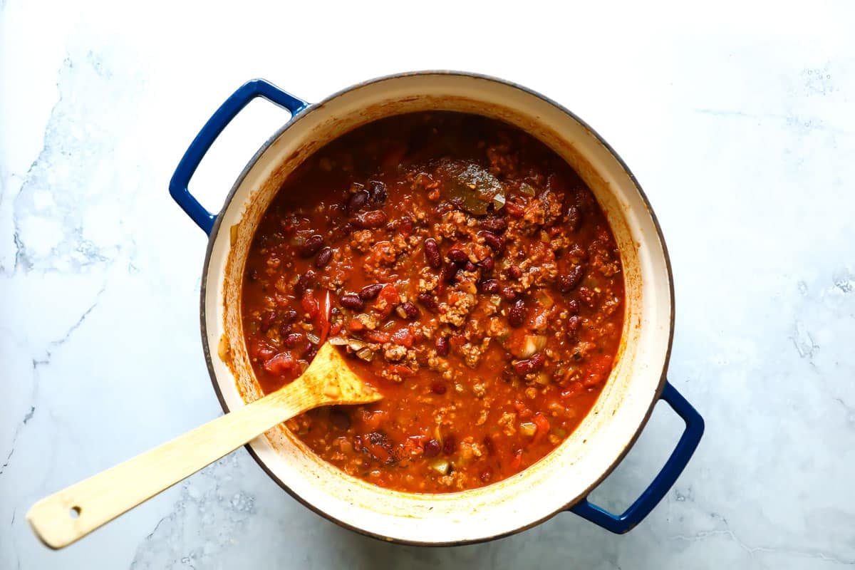 Turkey chili in a Dutch oven with a wooden spoon in it.